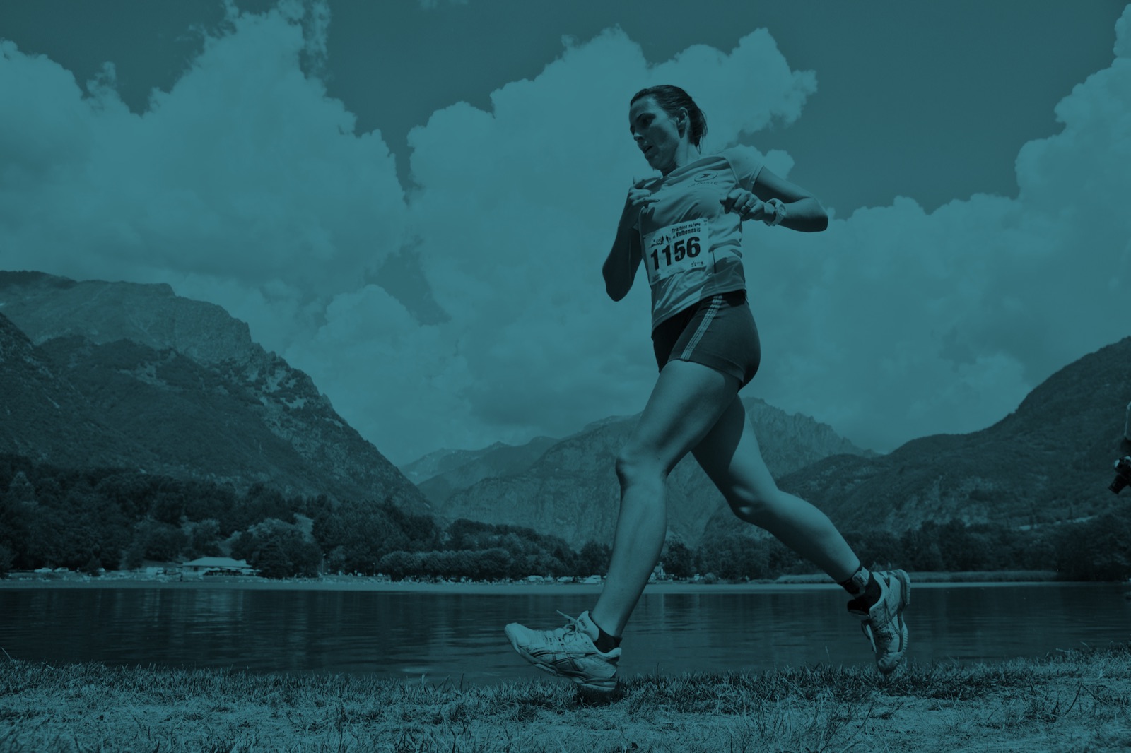 Trail runner wearing a race bib along a mountain lake
